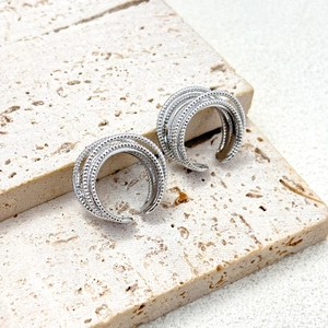 Detailed close-up of multi-layer silver ear cuffs with beaded texture on stone