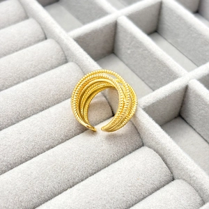Macro detail of gold-plated multi-layer stacked ring with textured bead and rope pattern
