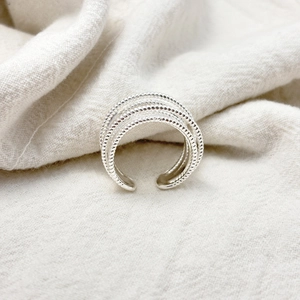 Detailed view of silver multi-layer beaded texture ring on beige fabric background