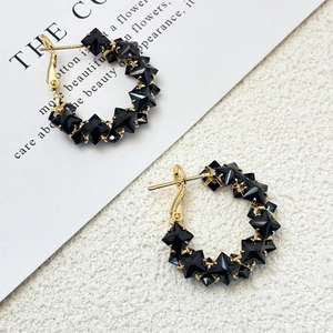 Close-up of gold s925 silver hoop earrings featuring black star-cut zircon crystals