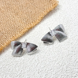 Gros plan sur des boucles d'oreilles nœuds argentées avec métal brossé et pierre de zircon