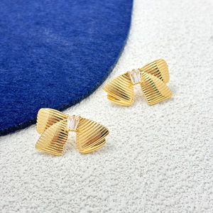 Boucles d'oreilles nœud dorées avec texture ondulée et zircons vue de dessus chic