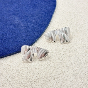 Gros plan détaillé des boucles d'oreilles nœud argenté avec zircon et métal texturé