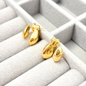 Macro view of gold teardrop earrings with a polished finish in a velvet jewelry box
