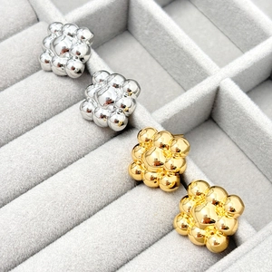 Spherical gold and silver beaded stud earrings set shown on a grey velvet jewelry display box