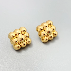 Close-up of gold-plated geometric cluster bead earrings with high-gloss mirror finish
