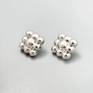 Macro detail of geometric silver beaded ball cluster earrings with metallic luster finish