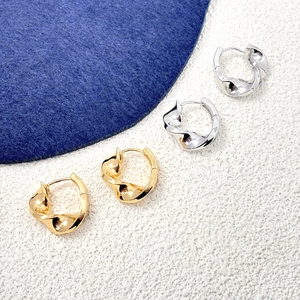 Detailed view of twisted spiral hoop earrings in 18K gold and silver finishes