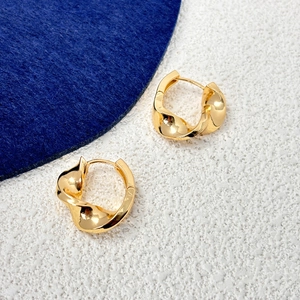 Detail of twisted 18K gold plated hoop earrings featuring a modern spiral design