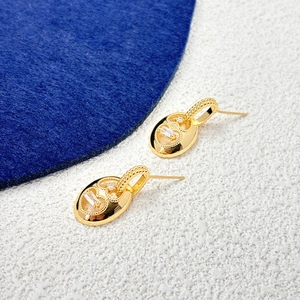 Detailed macro view of gold oval earrings with clear zircon stones and bead detailing