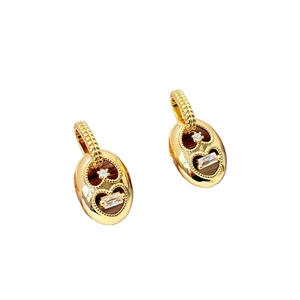 Detailed close-up of gold oval drop earrings with heart cutouts and zircon stones