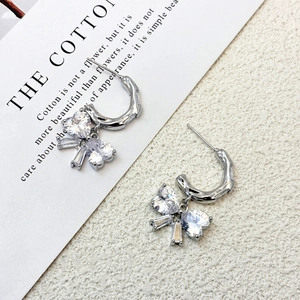 Detailed shot of bow-shaped silver earrings with sparkling heart-cut cubic zirconia
