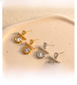 Detailed view of gold and silver stud earrings with large crystals and white faux pearls