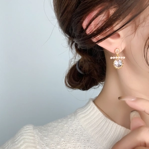 Detail of gold drop earring with round cut crystal and four small pearls on a model