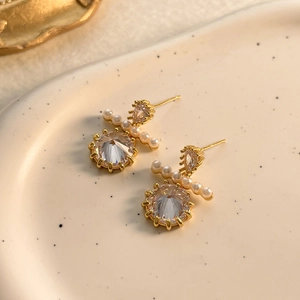 Close-up of elegant gold earrings with heart zircon, pearls, and round crystal drops