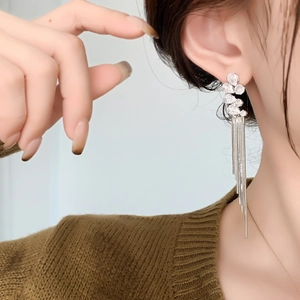 Close-up of elegant long tassel earrings with silver chains and sparkling zircon stones