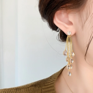 Detail of long gold tassel earrings with sparkling teardrop crystals on female model