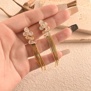 Close-up of elegant gold long tassel earrings with sparkling teardrop zircons on a hand