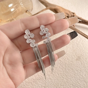 Close-up of silver long tassel earrings with sparkling teardrop zirconia held in hand