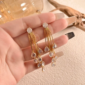 Close-up of elegant long tassel earrings with sparkling teardrop crystals and gold finish