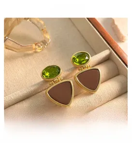 Detail of vintage gold earrings with green gemstones and brown enamel triangle charms