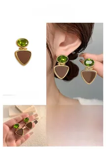Detail view of vintage geometric drop earrings with green gemstone and brown enamel