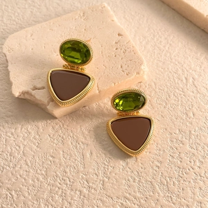 Detail of vintage gold earrings with green oval stones and brown triangular pendants