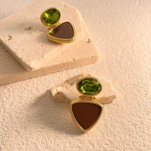 Detail of vintage gold earrings with green faceted stone and brown resin triangle inlay