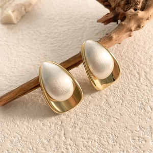 Macro shot of two-tone water drop earrings with gold finish and satin white surface
