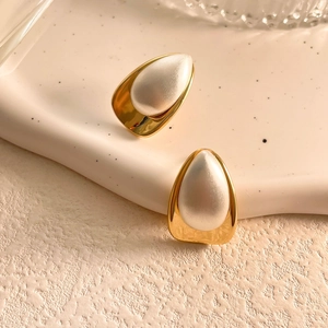 Detail view of two-tone gold and silver drop earrings with brushed texture and pearl finish
