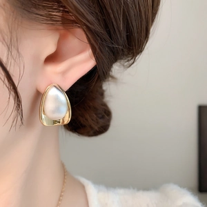 Close-up of gold and silver water drop earrings with brushed metal on a model's ear