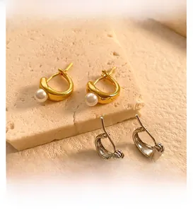 Detail showing irregular gold and silver C-shaped hoop earrings with elegant white pearls