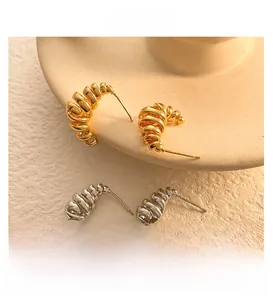 Detailed close-up of gold and silver spiral C-shaped earrings with textured ribbing