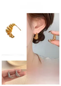 Detail view of gold and silver irregular spiral C-shaped stud earrings in a layered wire design