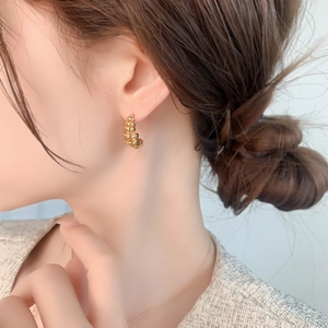 Close-up of a gold-plated spiral wire-wrapped C-shaped earring on a model's ear