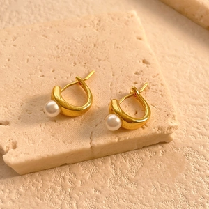 Detailed close-up of 18K gold plated irregular pearl hoop earrings on a stone display