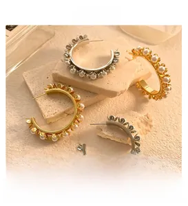 Détail de boucles d'oreilles créoles vintage avec perles blanches et finition dorée