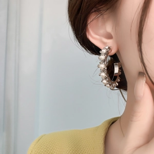 Gros plan de créoles vintage en C avec petites perles sur l'oreille du modèle