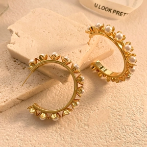 Gros plan de boucles d'oreilles créoles perlées avec détails dorés sur un support