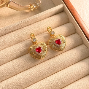 Detail of gold heart earrings with red crystal and diamonds in a jewelry box