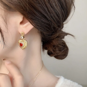 Vintage heart earrings with red crystal and 18k gold plating shown on a model