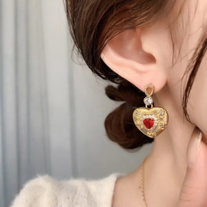 Vintage gold drop earrings featuring red heart gems and intricate sunburst textures