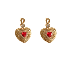 Detail of 18K gold plated heart earrings with red crystal and star pattern textures