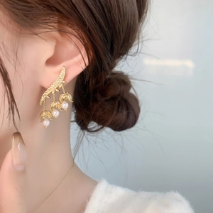 Macro detail of gold lily of the valley earrings with pearls and pavé cubic zirconia