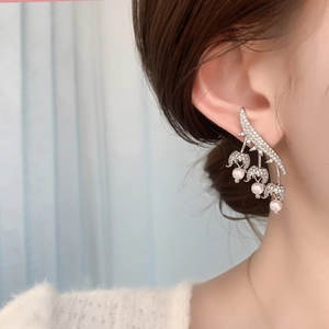 Close-up of sparkling flower bud earrings with pearls and zircons on a model