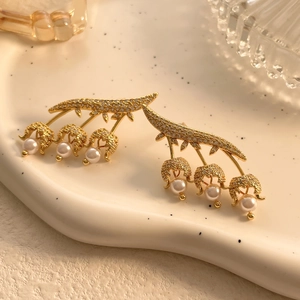 Close-up of golden lily of the valley earrings with micro-inlaid zircons and round pearls