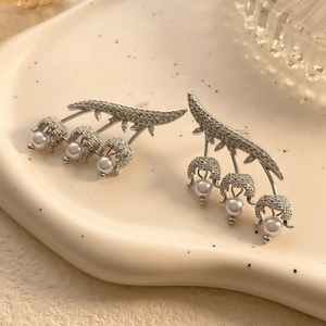 Macro shot of lily of the valley earrings with pavé zircons and hanging white pearls