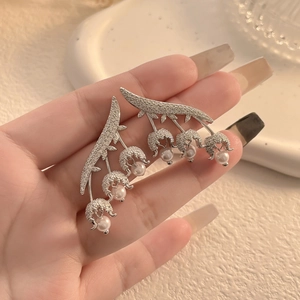 Detail of lily of the valley earrings with pearls and pavé cubic zirconia on hand