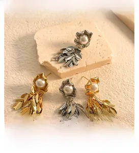 Macro detail of vintage leaf tassel earrings with white pearls and polished metallic finish