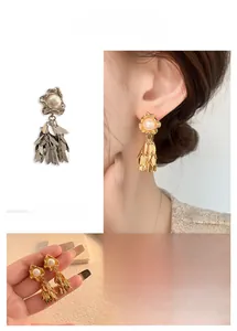 Detailed close-up of leaf tassel earrings with white pearls in gold and silver finishes